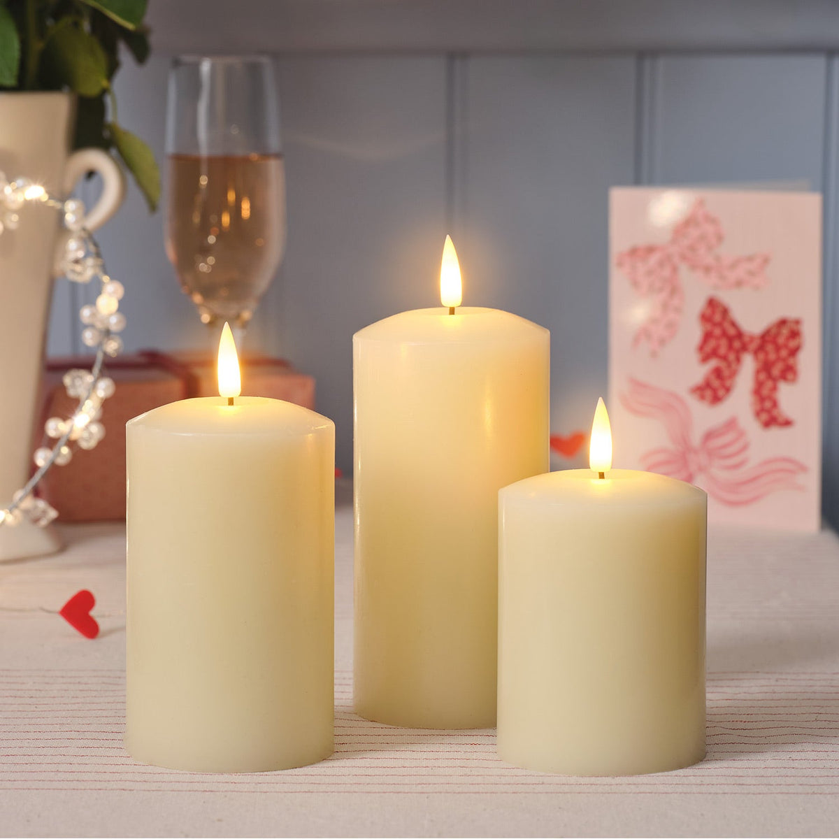 Three LED candles of different sizes on a table